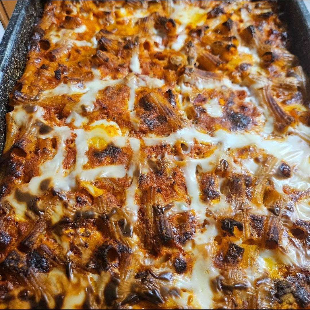 Teglia di pasta al forno dorata con mozzarella filante